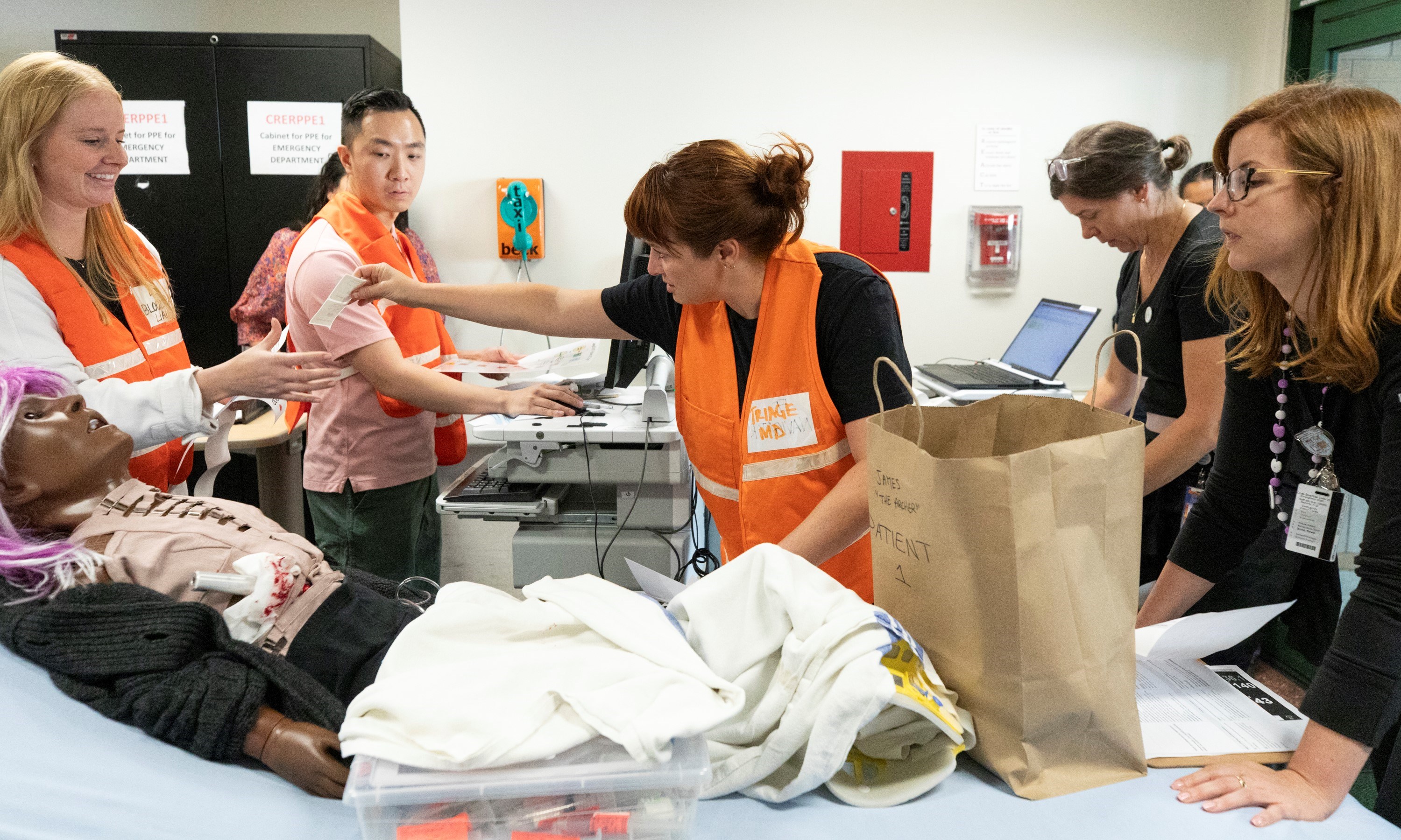 A simulated patient arrives in the ambulance bay at SickKids as two nurses and an ED physician triage them.