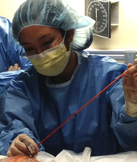 Dr. Jennifer Quon in full surgical garb, performing a procedure on an non-pictured patient.
