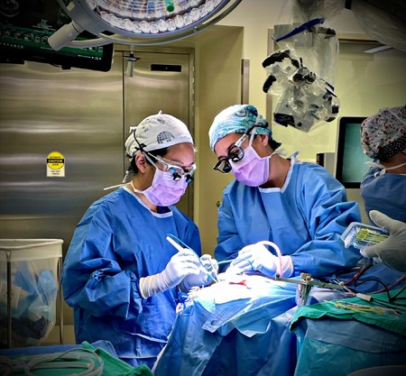 Dr. Jennifer Quon and another person, both in surgical garb, in the middle of an operation.