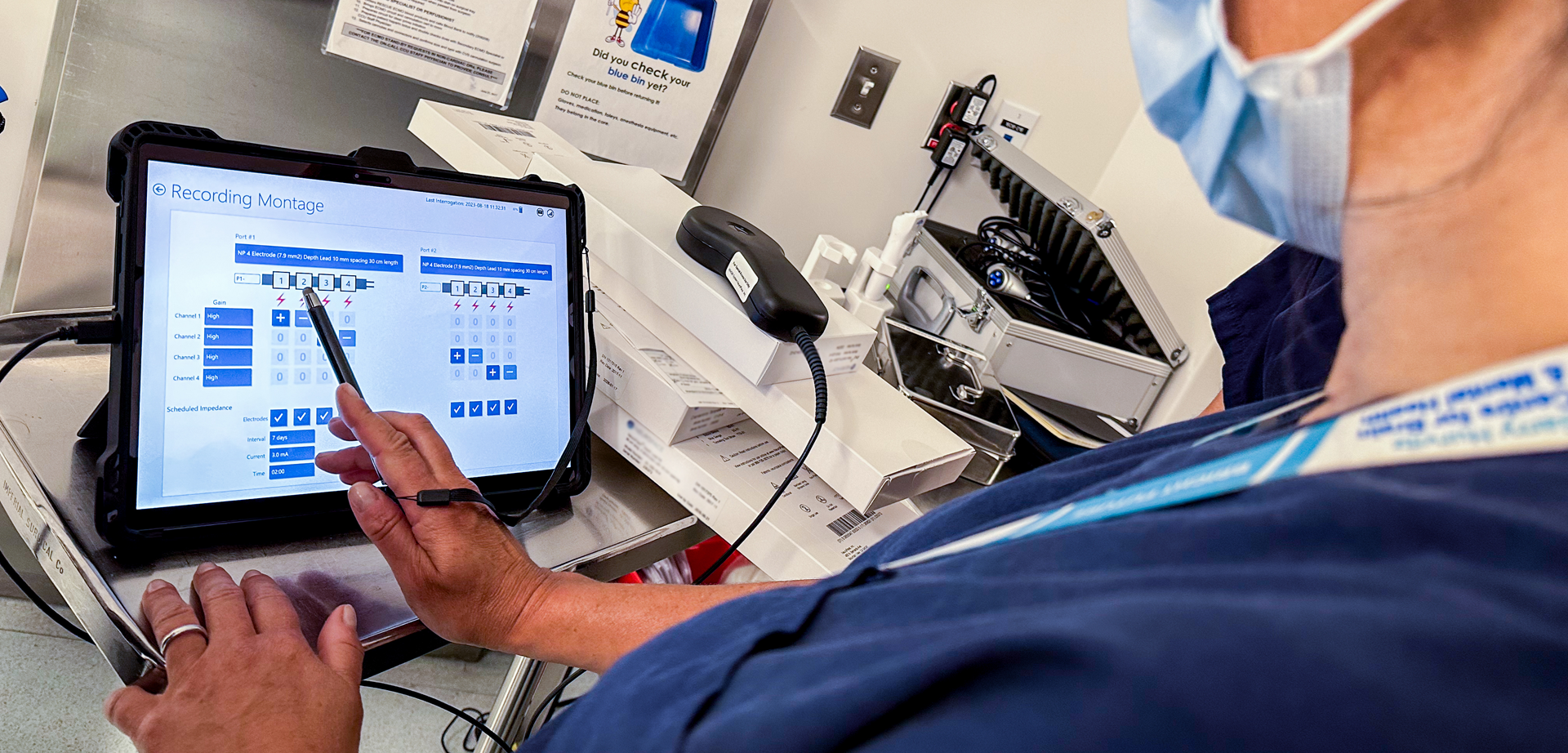 A person in hospital wear pointing to an interface displayed on an iPad.