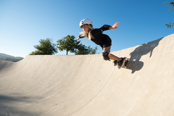 A child in a helmet and on a skateboard ramp