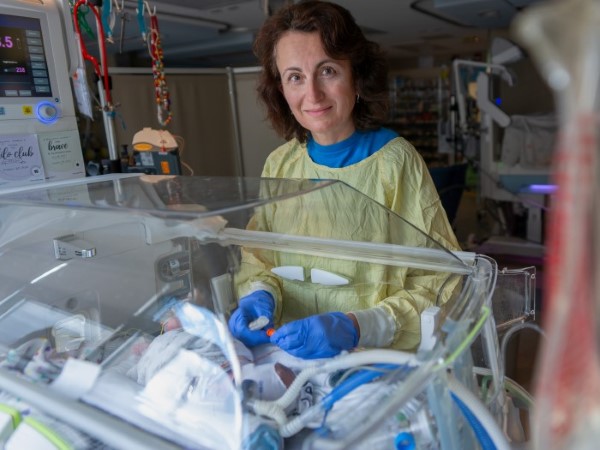 Maya Yevel, a nurse, stands beside a baby in an incubator in SickKids NICU..