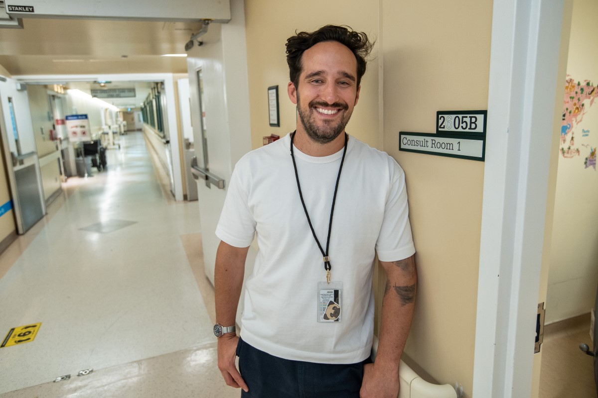 Caleb leads against a wall with a sign that reads "Consult room 1."
