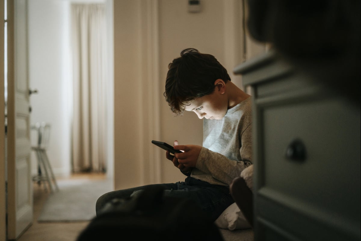 Child sitting and looking at smartphone