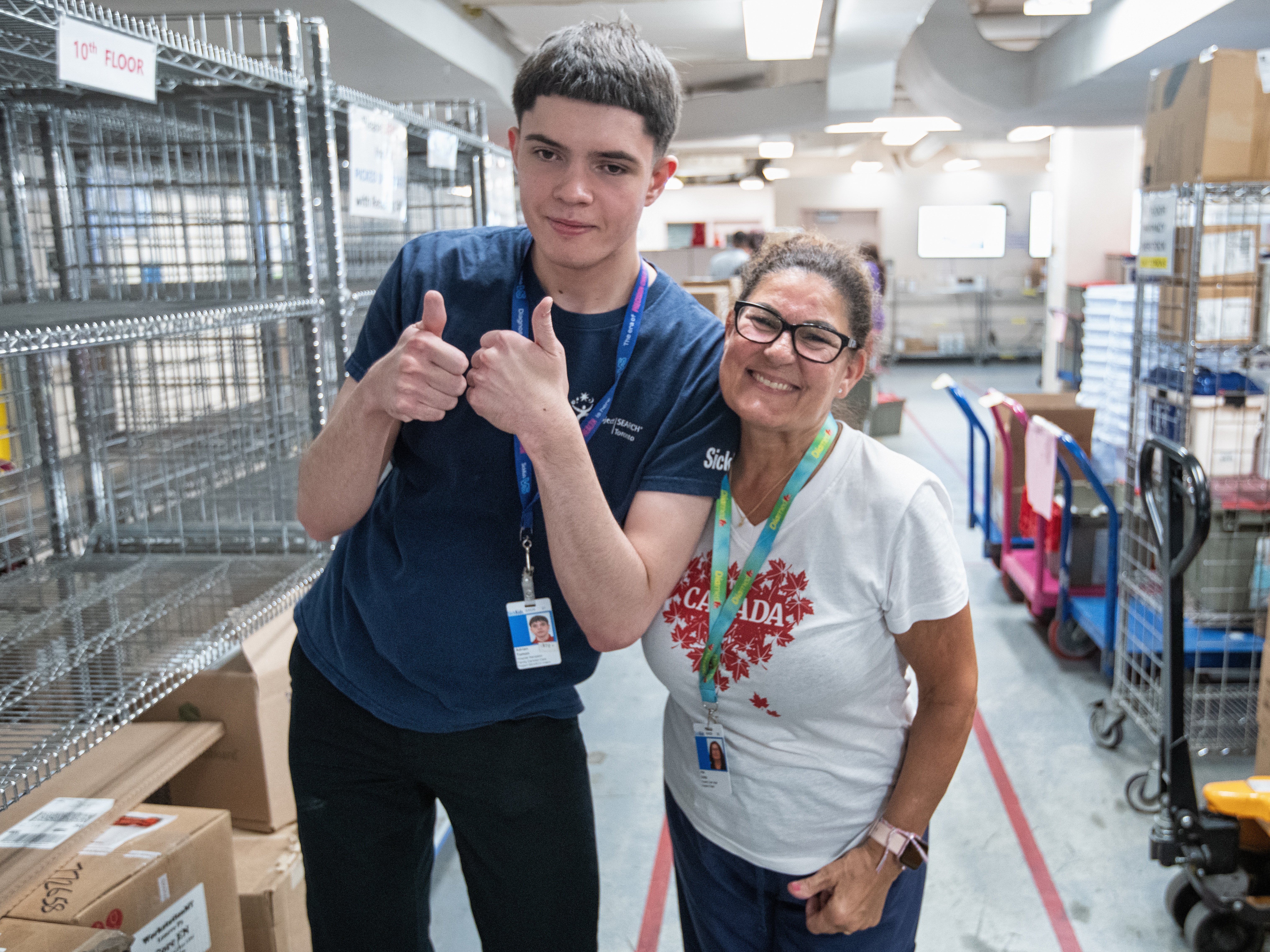 Two SickKids employees pose for a photo smiling and giving a thumbs up.