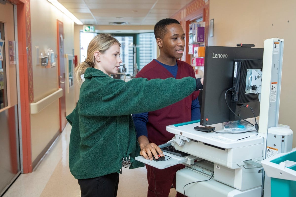 James and Nina point to a computer workstation in a hallway on 8B.