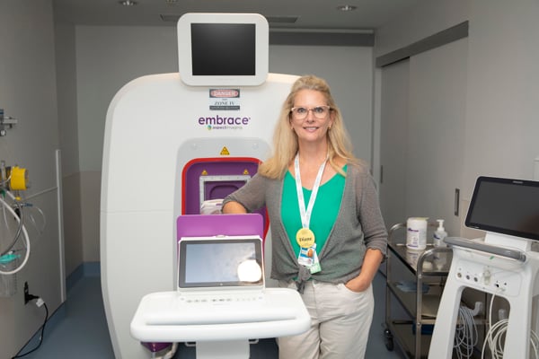 Diane Wilson, NP, stands in front of a neonatal MRI machine.