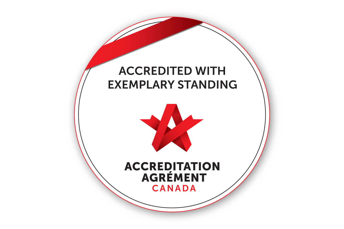Circle with red ribbon overlaid. Text states: Accredited with exemplary standing. Accreditation Canada.