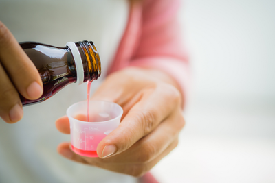 Liquid is poured from a bottle in to a measuring cup.