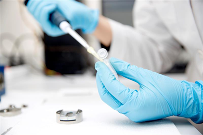 Gloved hands holding a pipette