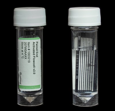 Two small bottles with plastic screw-on caps. The label on the first bottle reads, "Paired End Activated Flowcell v2.0". The second bottle shows the inside of the bottle, which contains a black rectangular frame submerged in a clear liquid.