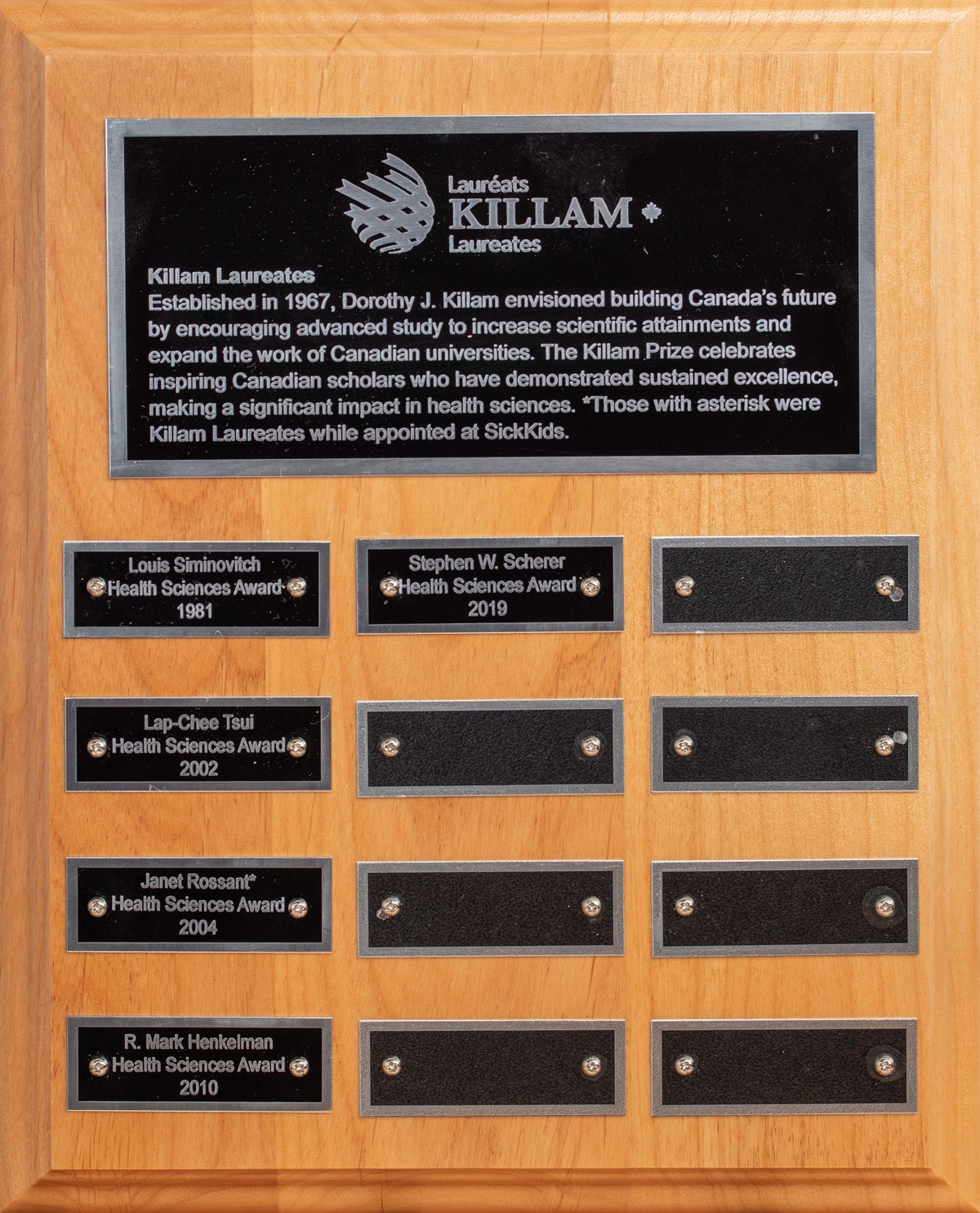 A wooden plaque of the various Killam awards that have been awarded over the years engraved on black metal plating.