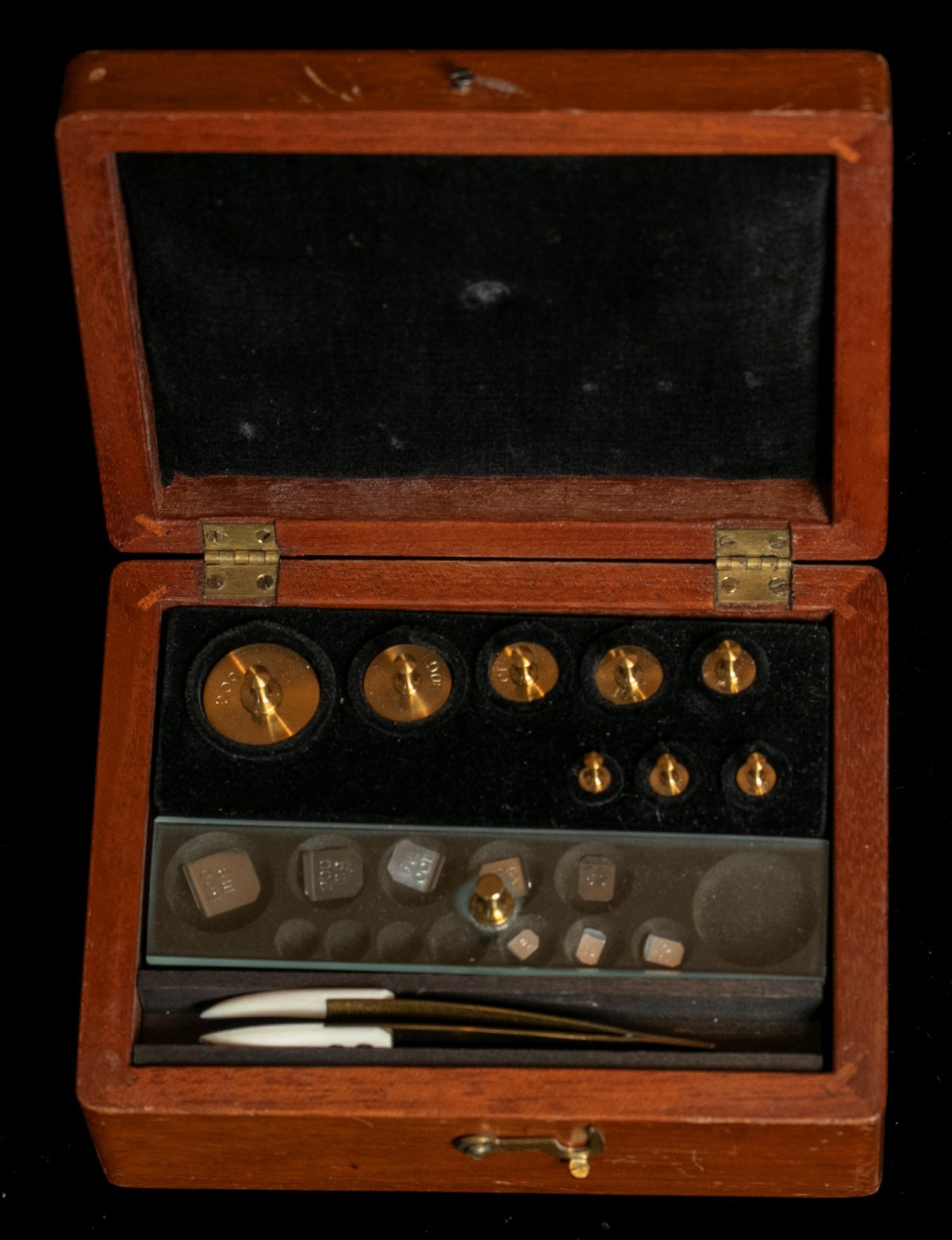 A wooden box containing a set of metal weights.