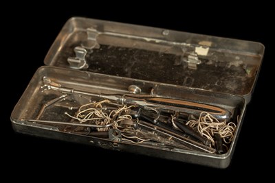 An open rectangular metal box containing a set of surgical instruments.